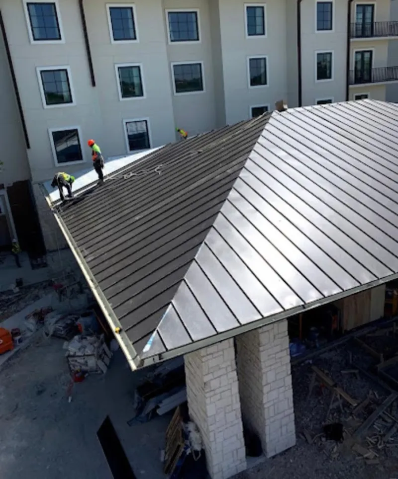Crew installing standing seam metal roof panels on a commercial project in Powdersville